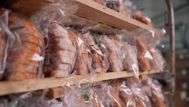 Rack with ready packed fresh bread close-up. Bread factory indoors. Food production