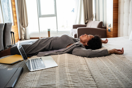 The businesswoman enters her hotel room and, with a sense of relief, sinks onto the hotel bed. The comfort of the room offers a well-deserved moment after a long day of conferences and meetings.