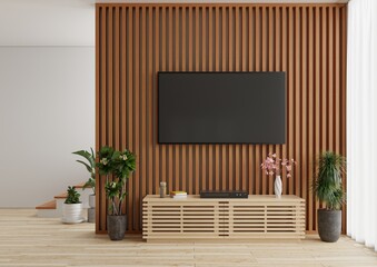 TV on a wooden wall in a living room decorated with plants and a video player on a wooden table in front.3d rendering