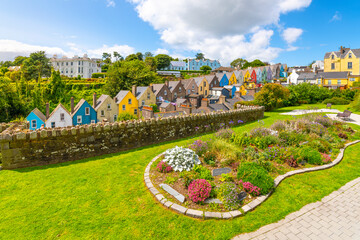 The picturesque and colorful Deck of Cards, a row of brightly painted townhomes, is seen from the Garden of Reflection park in the coastal town of Cobh, Ireland, Cork County. - obrazy, fototapety, plakaty
