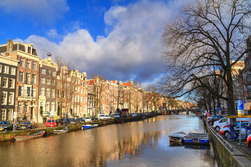 Fototapeta na wymiar Cityscape on a sunny winter day - view of the houses and the city canal with boats in the historic center of Amsterdam, The Netherlands