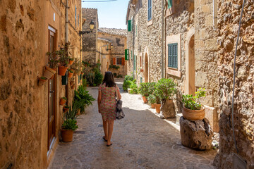 50 year old woman with gray hair walking through the narrow and ornate streets of Valldemossa (Mallorca, Spain) on a sunny summer morning