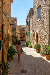 Fototapeta na wymiar 50 year old woman with gray hair walking through the narrow and ornate streets of Valldemossa (Mallorca, Spain) on a sunny summer morning