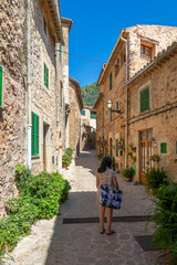 Fototapeta na wymiar 50 year old woman with gray hair walking through the narrow and ornate streets of Valldemossa (Mallorca, Spain) on a sunny summer morning