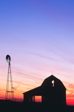 Beautiful sunset of a windmill and barn silhouetted in Indiana