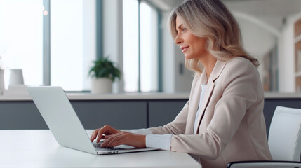 Beautiful senior adult woman working on laptop computer in office