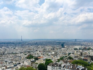 Obraz premium Overlooking all of Paris and the Eiffel Tower on a sunny Summer day with a fluffy white cloud filled sky