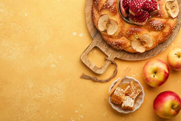 Jewish Holidays - Rosh Hashanah or Rosh Hashana. Pomegranate, apples, honey and round challah on rustic yellow table background. Jewish Autumn celebration. Shana Tova. Yom kippur concept. Top view.
