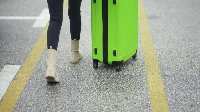 Young traveler woman walk at airport pushing thesuitcase, slow motion