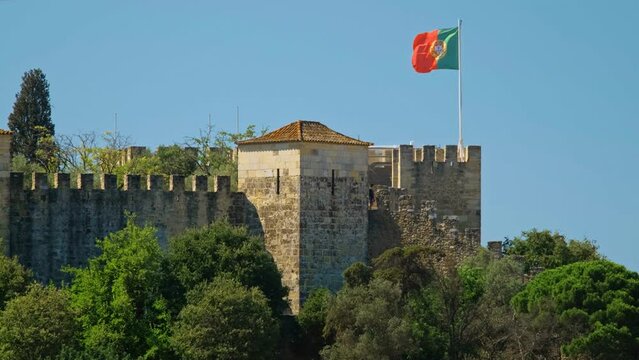 Saint George Castle Castelo de Sao Jorge in Lisboa, Portugal with walking tourists and large Portuguese flag