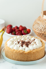 Banoffee cake with banana and caramel sauce filling sprinkled with grated dark chocolate on the white marble background. Flat lay. English traditional pie