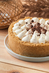 Banoffee cake with banana and caramel sauce filling sprinkled with grated dark chocolate on the wooden rustic background. English traditional pie
