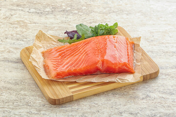 Raw salmon fillet over board