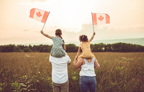 A Patriotic family waving Canada flags on sunset - Powered by Adobe