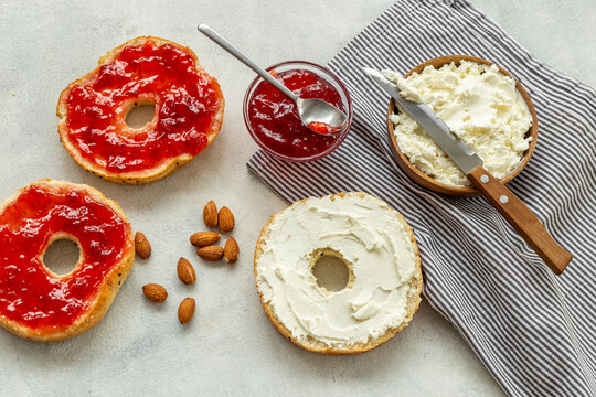 Fresh baked bagels with berry jam and cheese cream. Homemade bread background
