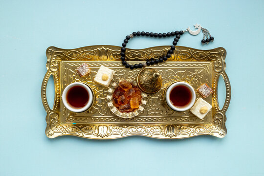Ramadan party table with tea on bronze tray and Muslim rosary with a crescent moon