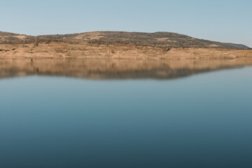 Mirror of water from a huge lake reflecting a mountain and blue sky.