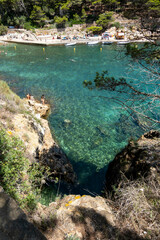 Image of the crystal-clear waters of the Mediterranean Sea in the Costa Brava, with the sun's reflection on its waves breaking against the rocks.