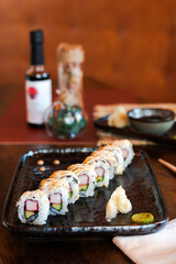 Asian food assortment. California sushi rolls placed on ceramic oriental style plates. Soy souce and chopsticks on sides