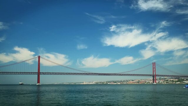 View of 25 de Abril Bridge famous tourist landmark of Lisbon connecting Lisboa to Almada on Setubal Peninsula over Tagus river with tourist boats yachts and vessels moving. Lisbon, Portugal
