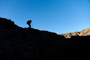 Silhouette of a backlit unrecognizable hiker walking in the mountains in Mendoza, Argentina.