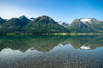 Hjelle, Norway: fjords landscape: panoramic view of  montains and glaciers reflecting in the fjords water