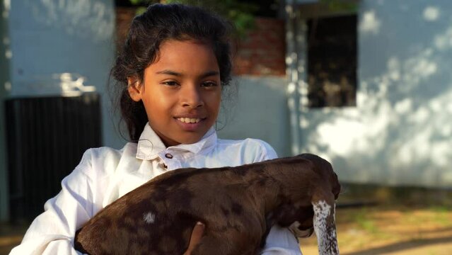 Asian kid holding a white goat's looks at side of the camera. Agriculturist concept. Life in the countryside.