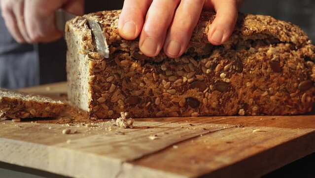 Cutting whole wheat bread into slices on a wooden work surface. Close-up.