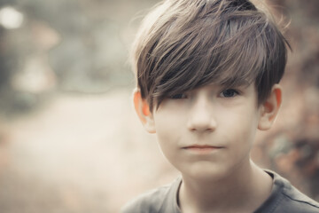Boy is looking at the photo camera. A child enjoys nature in the forest. Soft selective focus