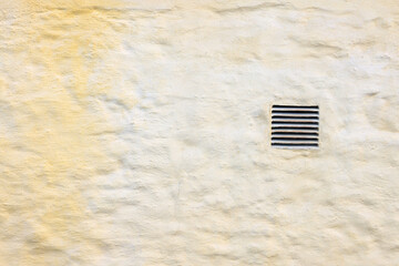 Image of an exterior dryer vent guard on a yellow painted wall