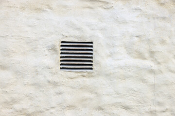 Image of an exterior dryer vent guard on a yellow painted wall