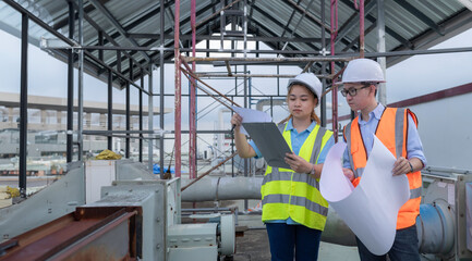 Two young engineers working together,Discuss the construction of a warehouse,See the construction drawings for the storage facility.