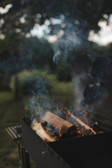 barbecue BBQ grill with flaming fire and ember charcoal on nature background, Flaming charcoal grill with open fire, ready for product placement. Concept of summer grilling, barbecue, bbq and party