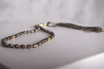 Black prayer beads with 33 knots made of stone on a matte surface on a white background