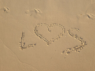 letters written in sand on exotic beach sea shore handwritten in a sandy texture background in summer. love, valentine, postalcard, concept, copy space