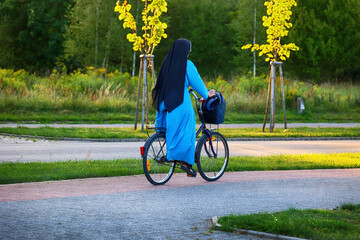 Zakonnica katolicka jedzie na rowerze przez park, 