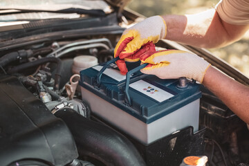 auto mechanic repairs a car. A mechanic removes a car battery from the box