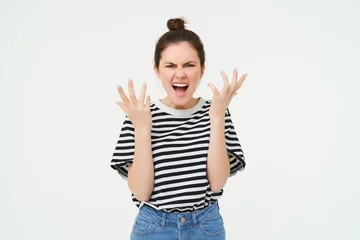 Fotobehang Image of angry woman shouts and shakes hands, stands in casual clothes over white background © Mix and Match Studio