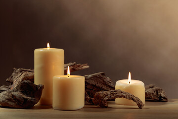 Burning candles and of old wooden snags on an old oak table.