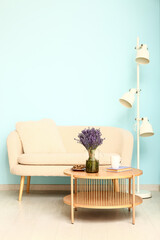 Interior of stylish living room with sofa, lamp, table and beautiful lavender flowers
