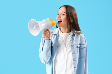 Young woman shouting into megaphone on blue background