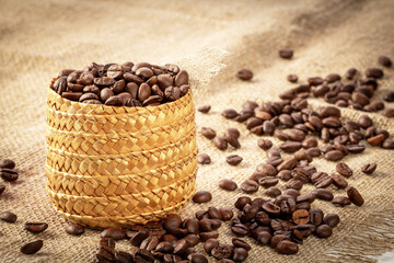 Cane basket filled with roasted coffee beans against the backdrop of a burlap napkin