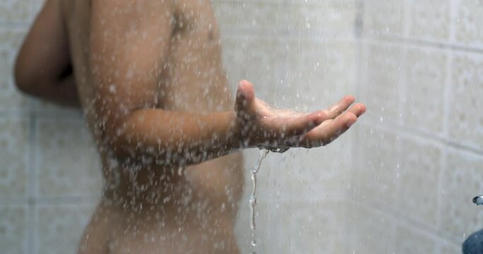 Droplets flowing in slow-motion 800 fps splashing into child hand while bathing during bath routine, kid washing body in dreamy scene