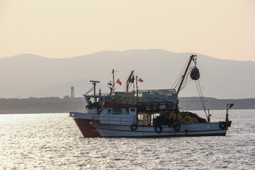 Fish boat trawler with fisher net on the sea in the morning with sky background. 