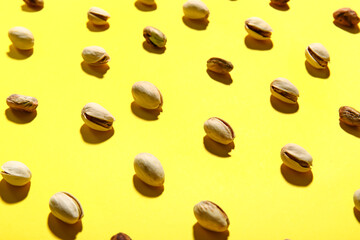 Tasty pistachio nuts on yellow background