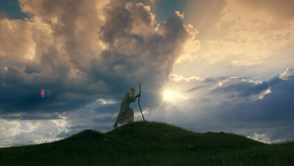 Fototapeta na wymiar Jesus Christ silhouette ascending a hill shrouded in twilight.