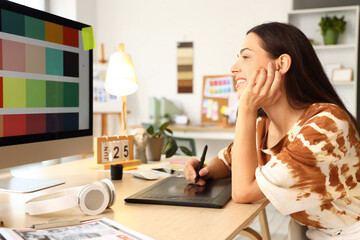 Female interior designer working with graphic tablet at table in office