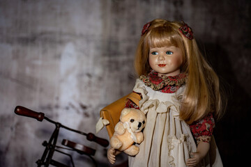 Realistic porcelain antique vintage girl doll or toy,  blonde hair and vintage dress with bicycle. Hand made