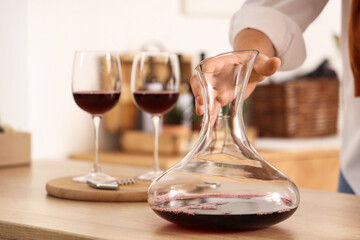 Sommelier with decanter of wine in kitchen at home, closeup