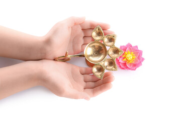 Female hands with diya lamp and lotus flower for celebration of Divaly isolated on white background